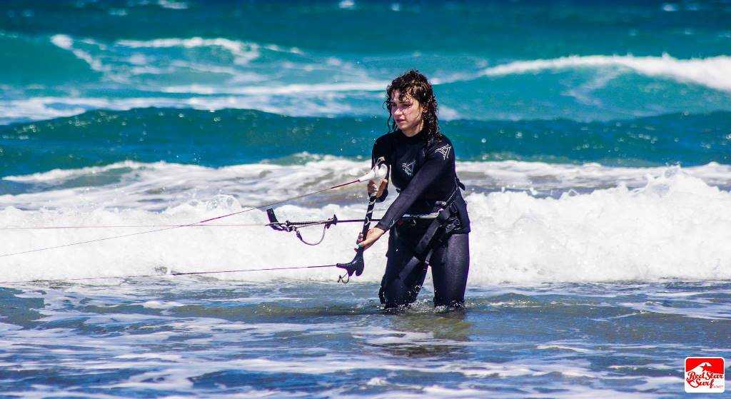 Kursant kitesurfingu w wodzie z barem w rękach