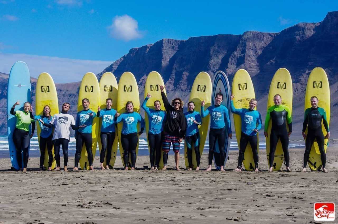 Grupa surferów z deskami pod klifami Famary