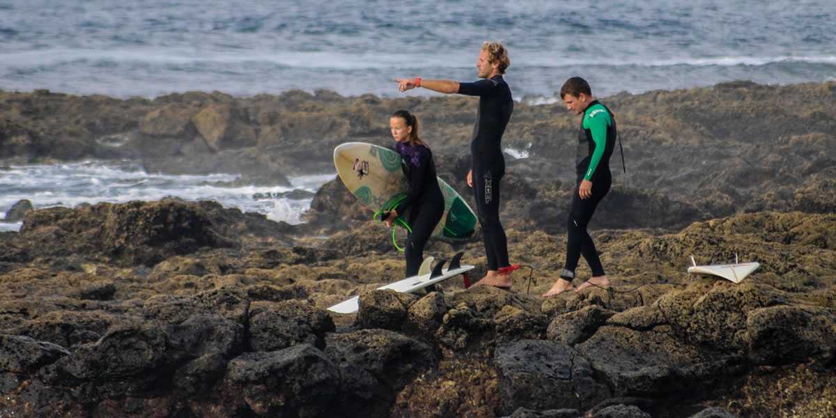 Surferzy na skałach lawowych obserwują rafę na zachodnim wybrzeżu