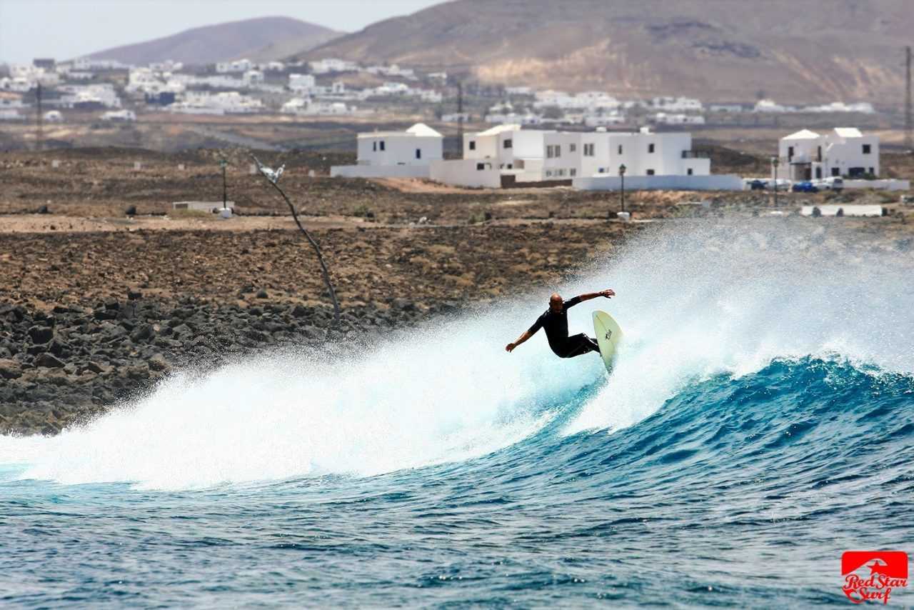 Surfer na fali przed wioską Caleta de Famara