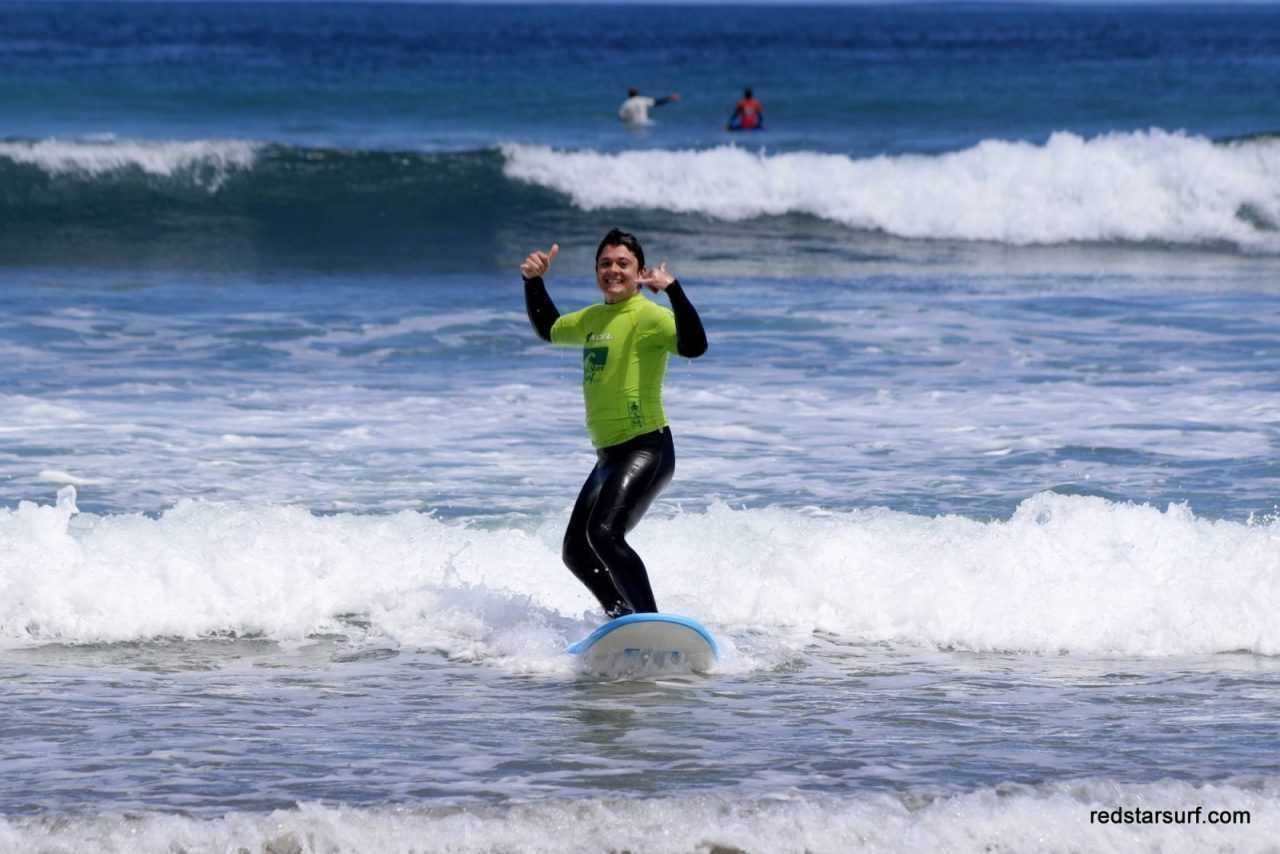 Początkująca surferka wstaje na fali w Famarze, Lanzarote