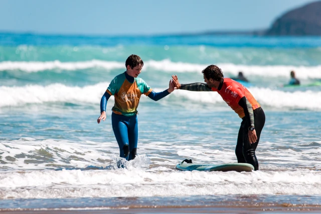 Kid standing up on a surfboard during a children’s surf lesson at Famara beach
