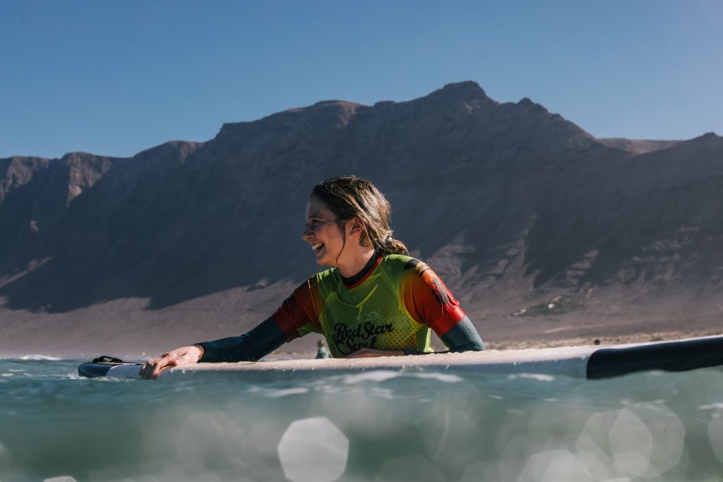 Surfař pádluje na pláži Famara během lekce pro mírně pokročilé