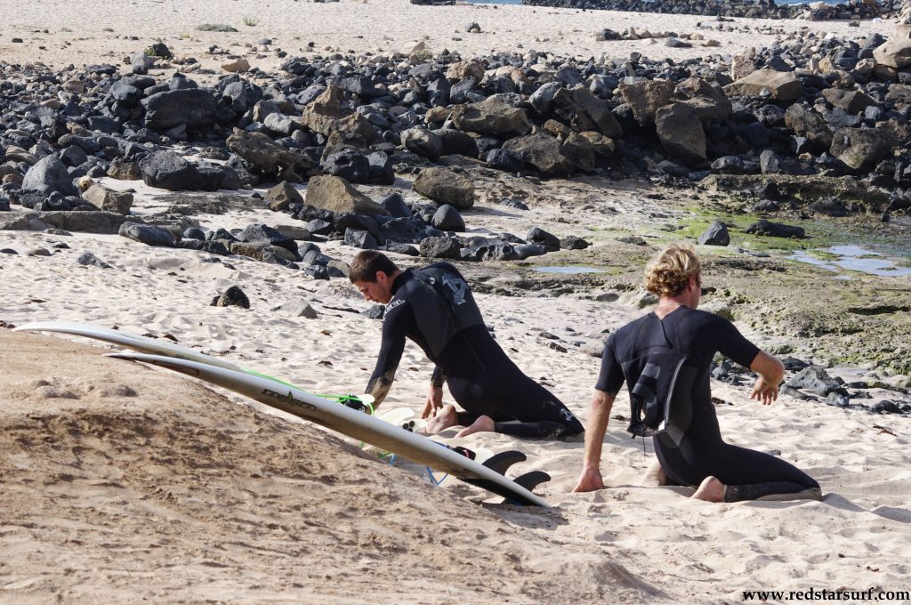 Uczniowie rozciągają się na kamienistej plaży przed sesją