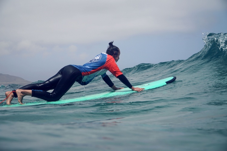 Surfer wiosłuje przez falę w Famarze