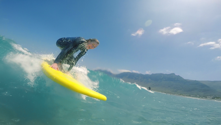Surfer na żółtej desce płynie na fali w Famarze