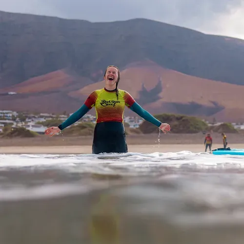 Uśmiechnięta dziewczyna na lekcji surfingu w Famarze, Lanzarote, z Red Star Surf