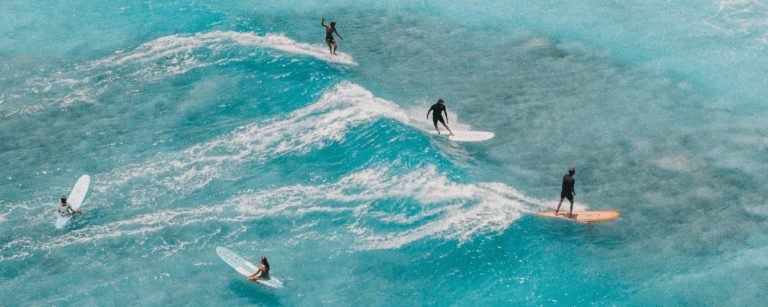 Surferzy na turkusowych falach na Lanzarote, widok z góry