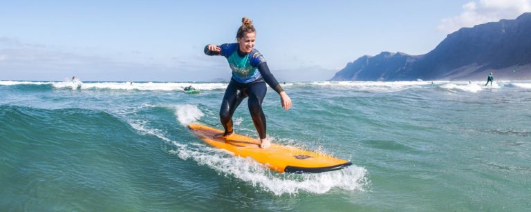 Początkujący surfer na desce soft-top na plaży Famara, Lanzarote