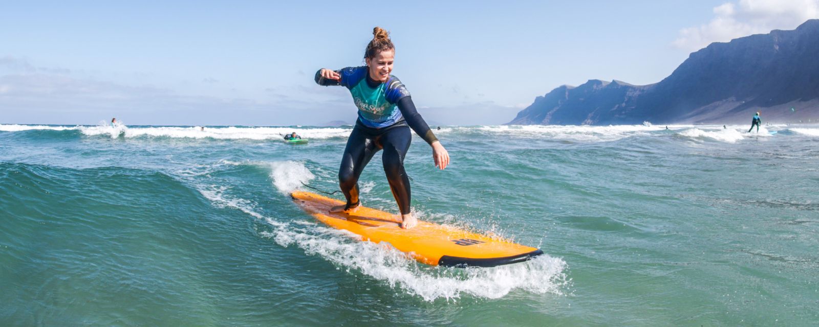 Początkujący surfer na desce soft-top na plaży Famara, Lanzarote