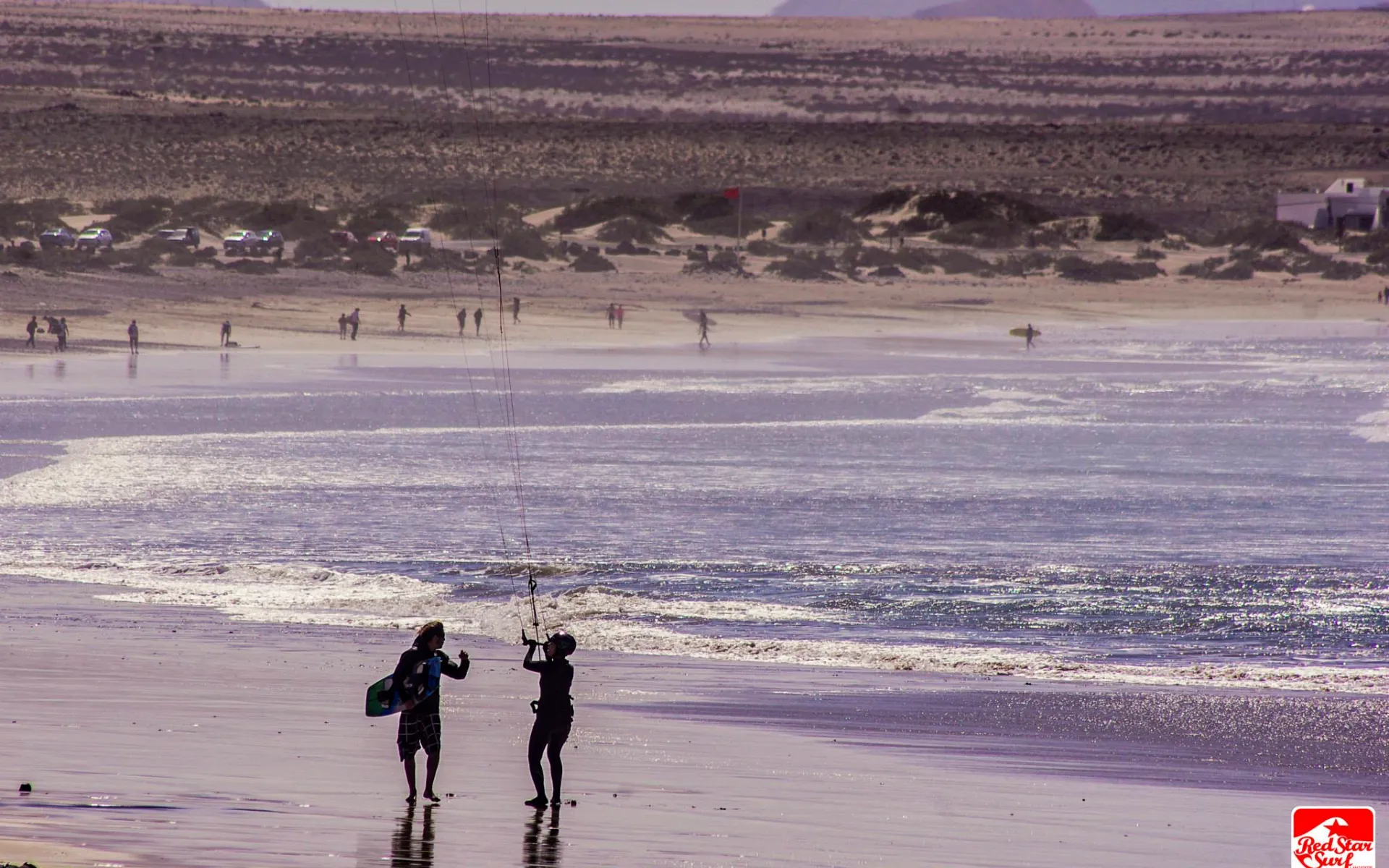 Kitesurfař jede podél pláže Famara pod útesy Risco, Lanzarote