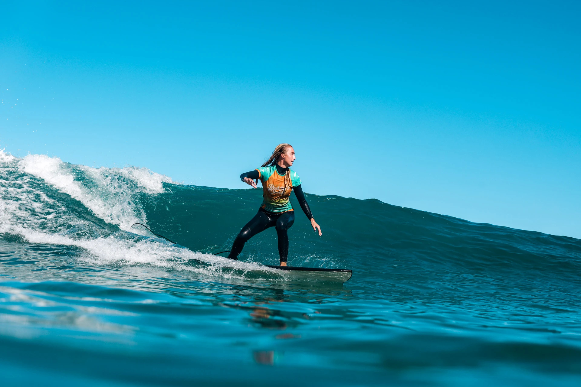 Średnio zaawansowany surfer na zielonej fali w Famarze, Lanzarote