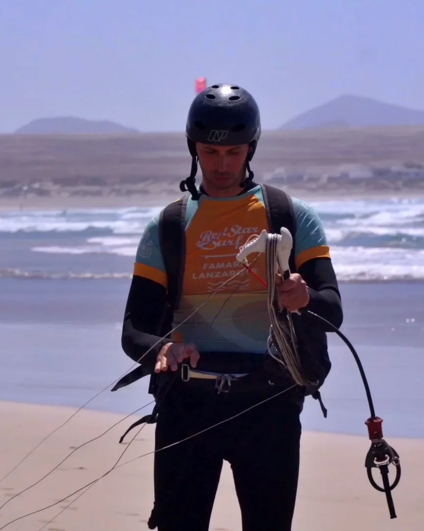 Istruttore di kite con trapezio e barra sulla spiaggia di Famara prima di una sessione di noleggio
