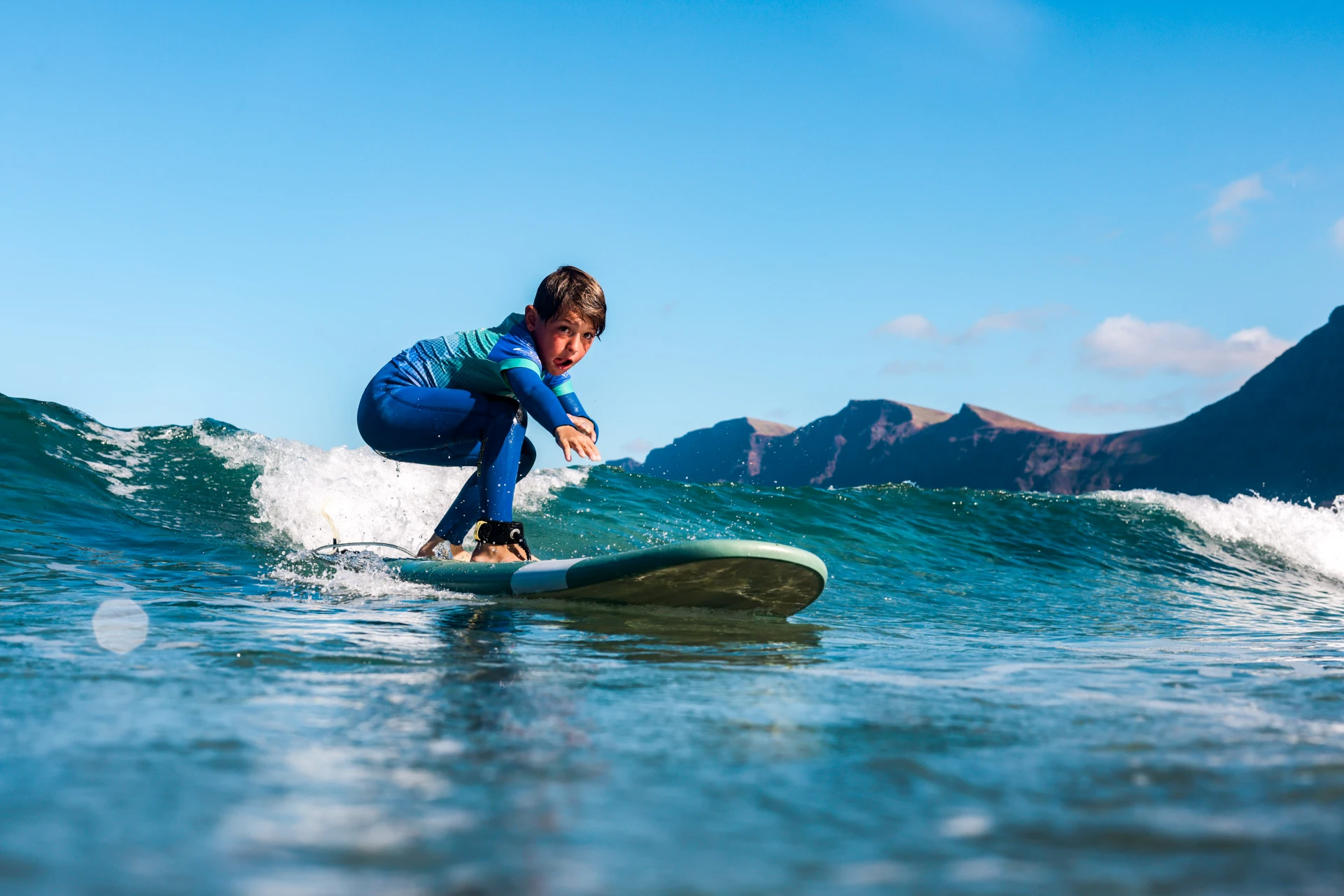 Young boy riding a wave during a kids surf lesson in Famara, Lanzarote