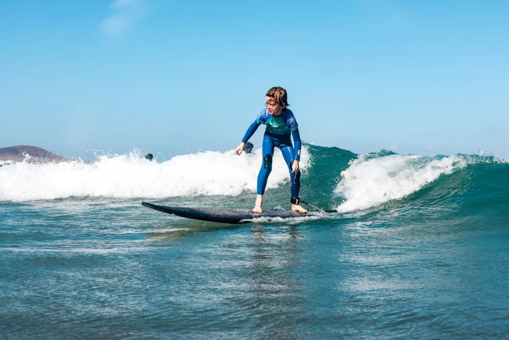 Child surfing a small wave at a kids surf lesson in Lanzarote