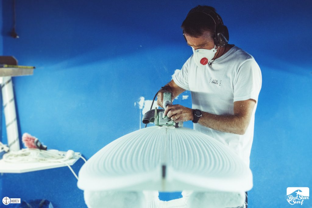 Shaper che pialla un blank di schiuma nella shaping room