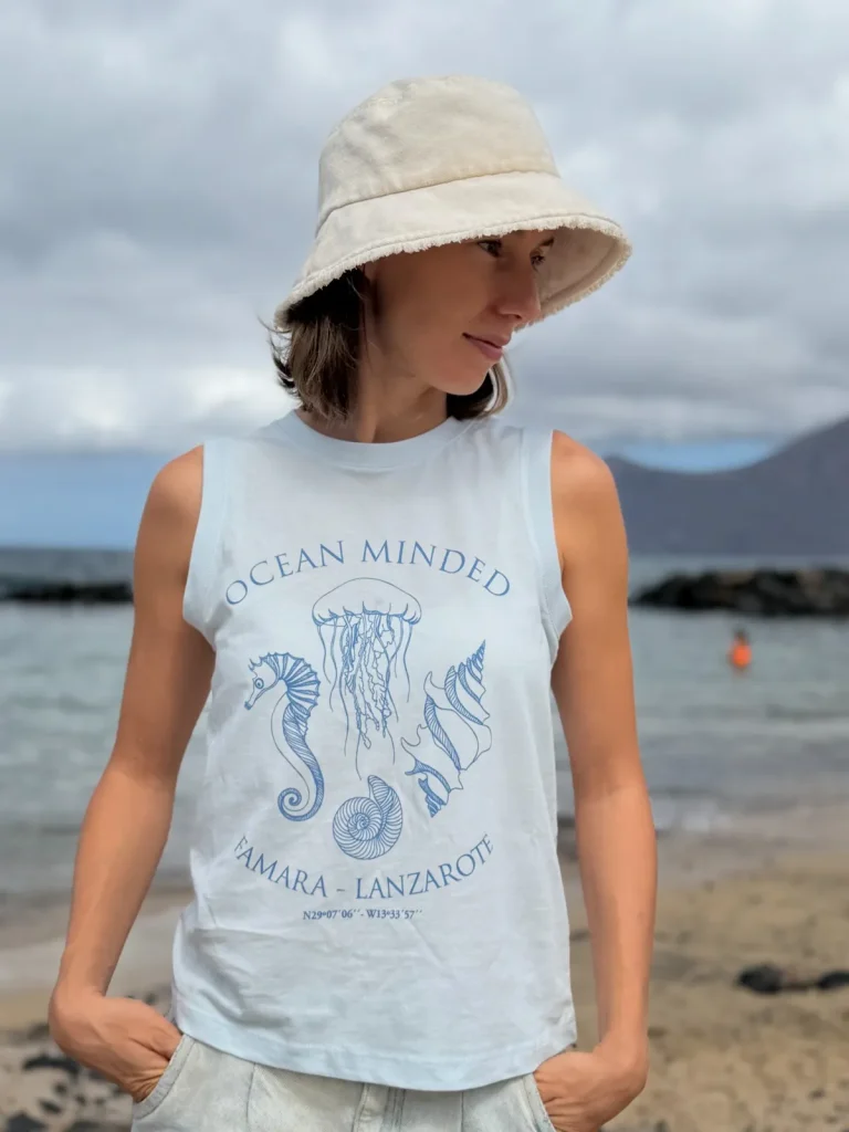 Hanna w jasnoniebieskiej koszulce bez rękawów Ocean Minded na plaży Famara