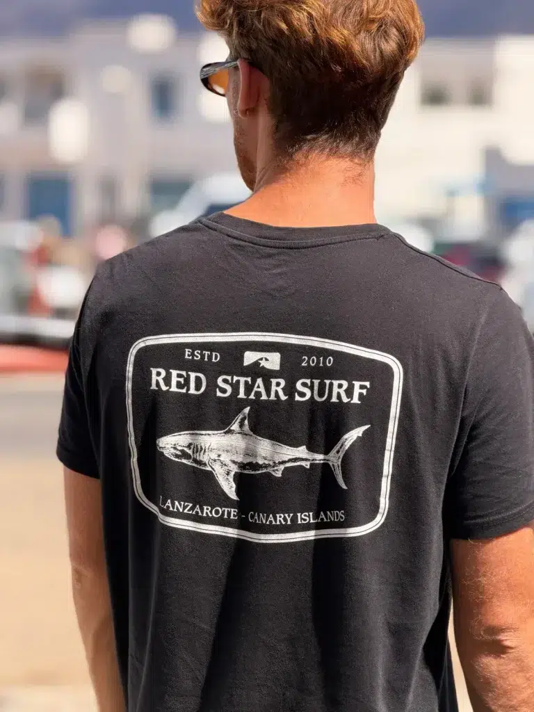 Luca od tyłu w czarnej koszulce Red Star Surf z rekinem